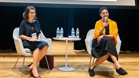 faculty member and alumna on stage at event
